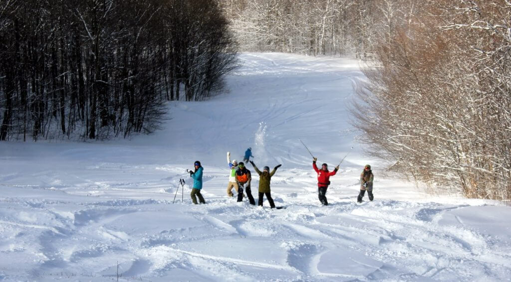 A group of Bolton Valley employees stand in the snow and pose for the camera