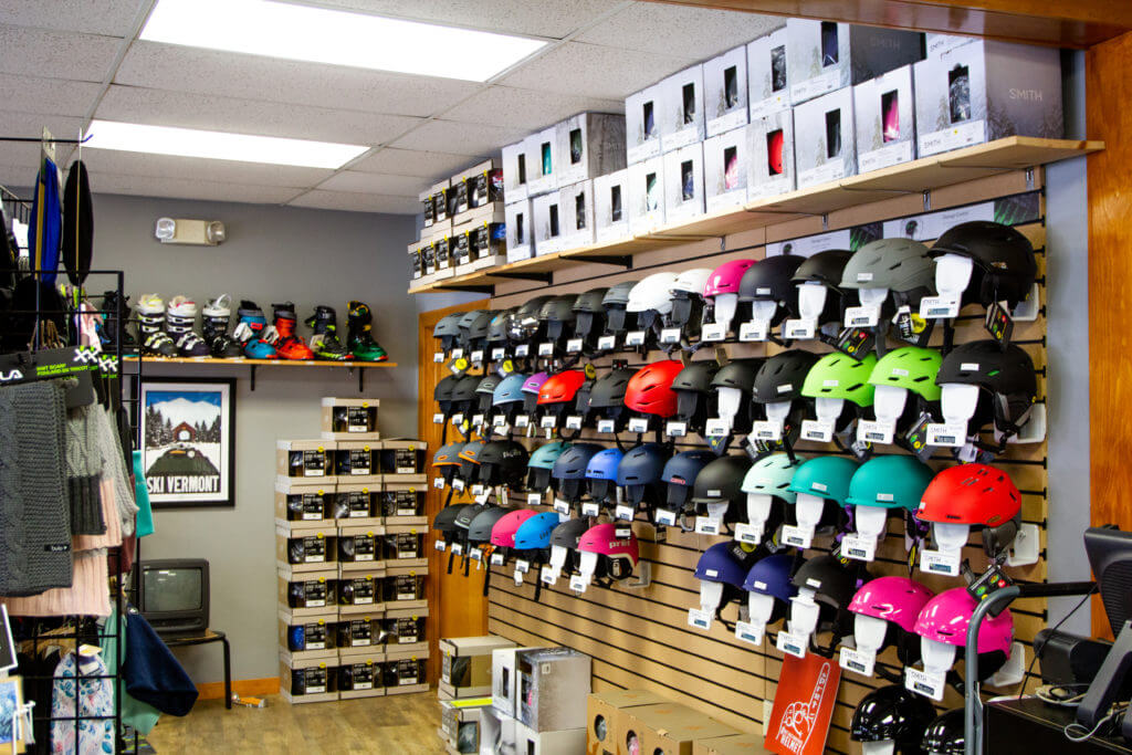 Interior of Ski shop with a wall display of colorful helmets next to a shelf with ski boots.
