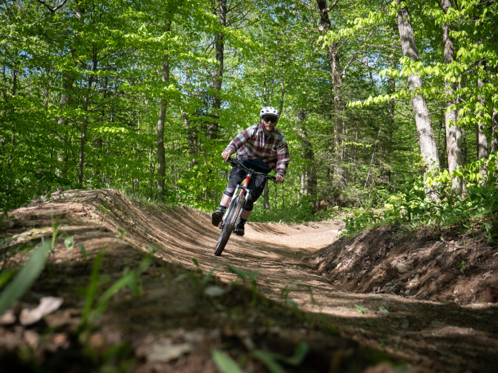Showing a biker biking through our trails that go through the woods.