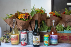 A display of wine, flowers, and freshly harvested vegetable