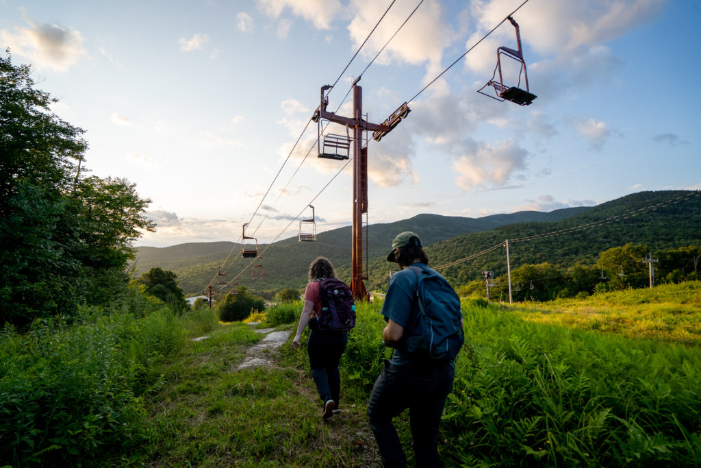 Two people hiking under a chairlift at sunset