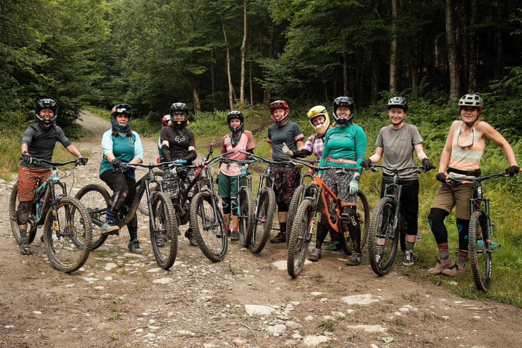 Group of women and their mountain bikes posing on a dirt trail