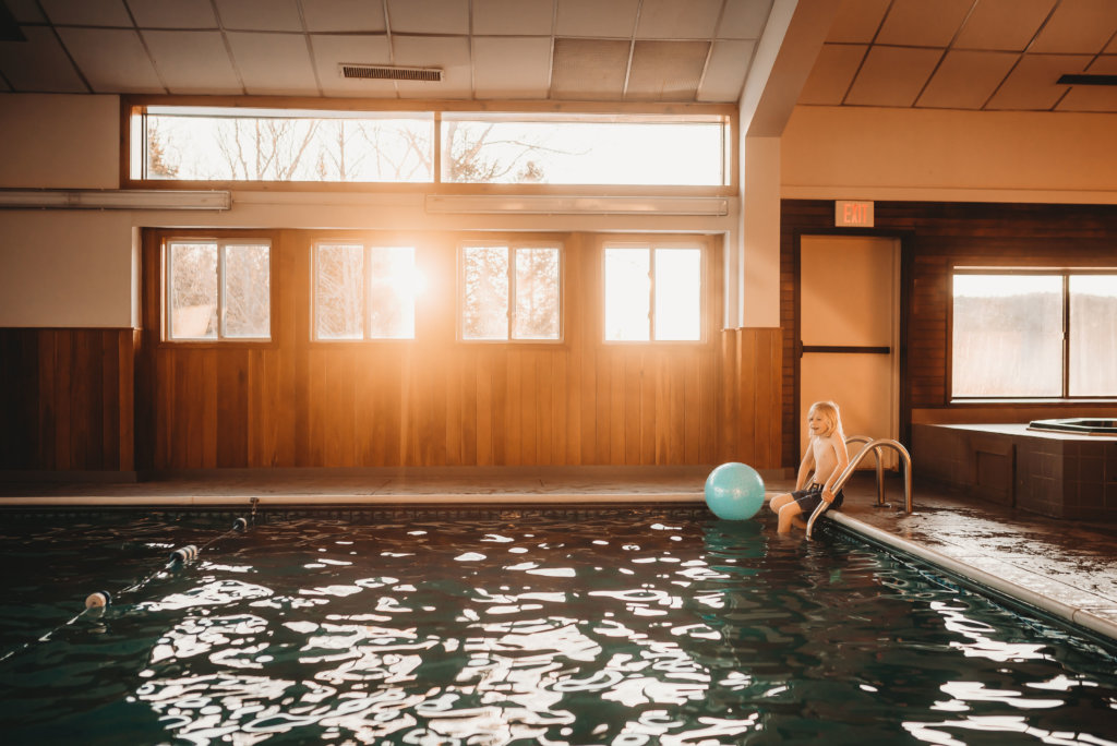 Child sits at corner of indoor pool at the Sports Center