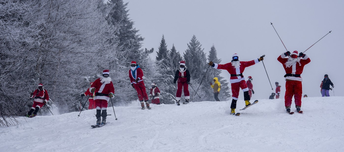 A group of skiers dressed as Santa Claus descend a ski slope in celebration