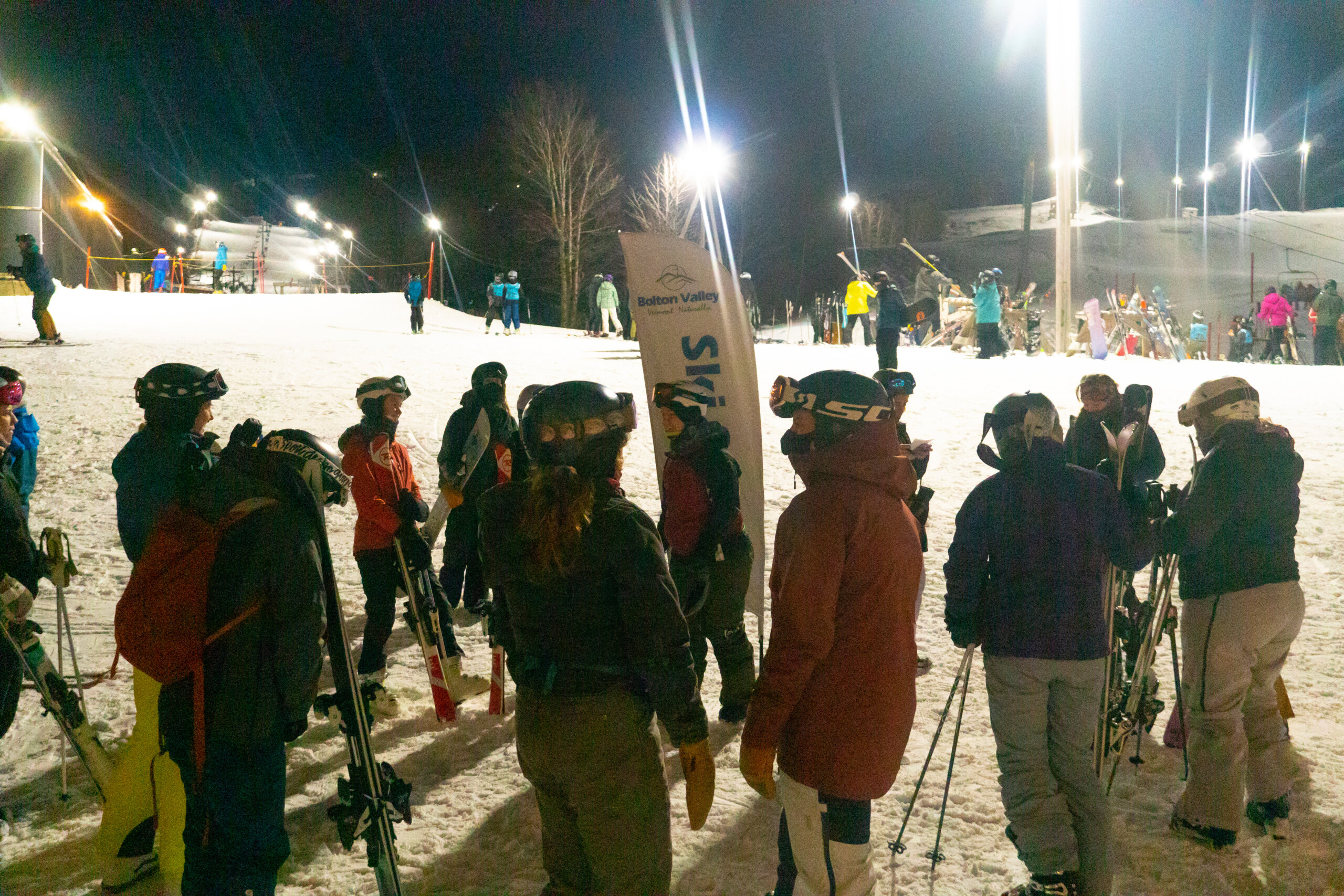 Group of women skiers and riders gather on the base of the mountain for night riding