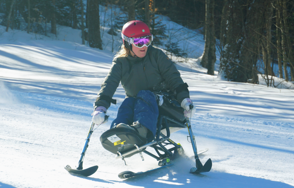 Adaptive skiier on the ski slopes with trees in the background