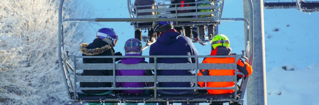 Outdoor ski lift with a family of four sitting in the chair headed up