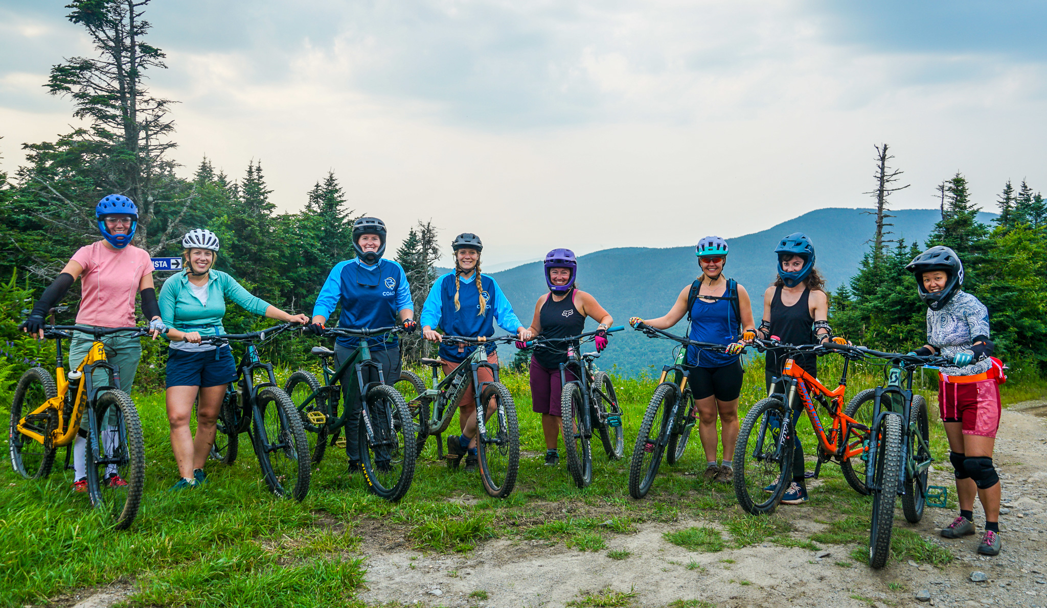 Group of women pose with bikes on a mountain peak